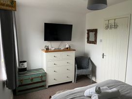 A bedroom with a television, dresser, and armchair at 22 Longstone Park Beadnell