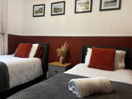 A bedroom with two beds and pictures on the wall at Heol Madog Porthmadog
