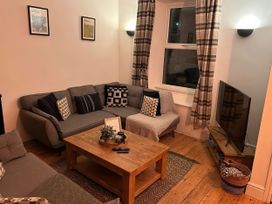 A living room with a sofa, coffee table, and television at Heol Madog in Porthmadog