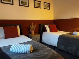 A bedroom with two single beds and framed pictures at Heol Madog in Porthmadog