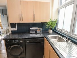 A kitchen featuring a sink, dishwasher, washing machine, and plants at The Causeway in Llandudno