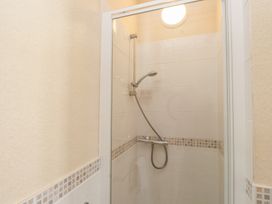 A shower with a glass door and wall tiles at The Causeway in Llandudno