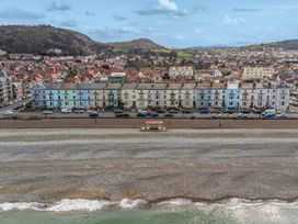 A beach with houses and cars along the promenade at The Causeway in Llandudno