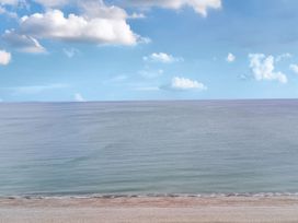 A beach with sand and ocean under a blue sky at The Causeway in Llandudno