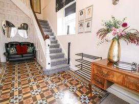 A hallway with a staircase, sofa, and console table at The Causeway in Llandudno