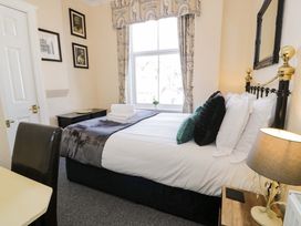 A bedroom with a bed, desk, chair, and window at The Causeway in Llandudno