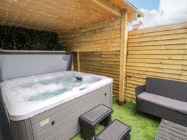 A hot tub with seating area and wooden fence at The Causeway in Llandudno
