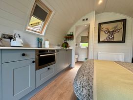 A compact kitchen and bedroom area with a bed and a painting of a deer at Oh Deer in Ashbourne