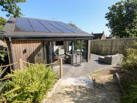 A garden view of a property with solar panels and outdoor seating at Cornerstones Brython in Tenby