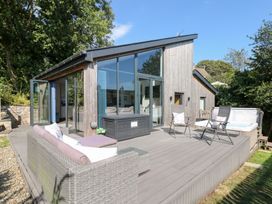 An outdoor area with a deck, sofa, chairs, and a hot tub at Cornerstones Brython in Tenby