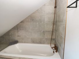 A bathroom with a bathtub and showerhead at 11 Brython Place in Tenby