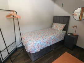 A bedroom with a bed, nightstand, and clothes rack at 11 Brython Place Tenby