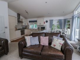 A living room with kitchen area and dining table at Seacroft in Stepaside near Kilgetty