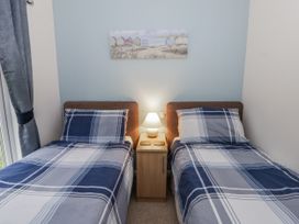 A bedroom with two beds and a nightstand at Seacroft in Stepaside near Kilgetty