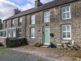 An exterior view of a house with a green door and seating area at Bryn Tirion in Moelfre