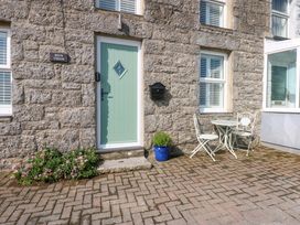 An outdoor area with a green door and a table with chairs at Bryn Tirion in Moelfre