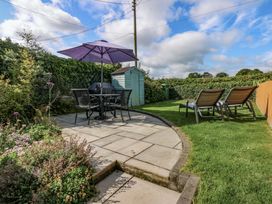 A garden with a table, chairs, and an umbrella at Bryn Tirion in Moelfre