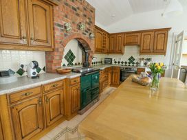 A kitchen with cabinets, oven, and coffee maker at Bwthyn Clai in Llangefni