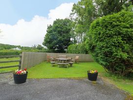 A garden with a wooden table and chairs at Bwthyn Clai in Llangefni