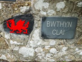 A dragon sign and a slate sign with Bwthyn Clai on a stone wall