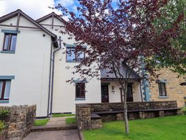 An exterior view of a building with benches and a tree at Mallard Cottage in Penrith