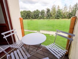 A balcony with a table and chairs overlooking grass at Mallard Cottage Penrith