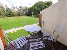 A balcony with a table and chairs overlooking a grassy area at Mallard Cottage Penrith