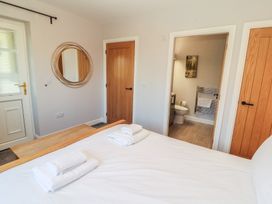A bedroom with a bed and mirror at Mallard Cottage Penrith