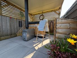 An outdoor covered area with a wood stove, a wooden tub, a drying rack with towels, and plants at No Deer in Ashbourne