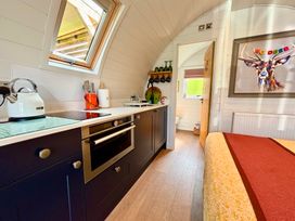 A kitchen area with a stove kettle and utensils next to a bedroom with a bed and a framed deer painting at No Deer in Ashbourne