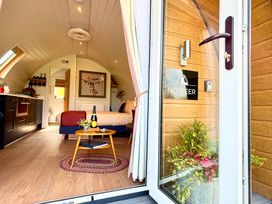 A small bedroom with a bed a round wooden table with a bottle and flowers and a kitchenette at No Deer in Ashbourne