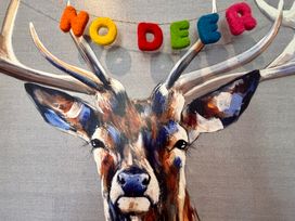 A close up of a painted deer head with colorful letters spelling no deer hanging between antlers at No Deer in Ashbourne