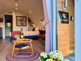 A bedroom with a bed, wooden table with a bottle and flowers, a deer painting, and a sign reading No Deer at No Deer in Ashbourne