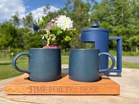 Two blue mugs and a blue French press on a wooden tray with flowers in a jar outdoors at No Deer in Ashbourne