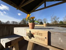 An outdoor seating area with a wooden table and flower pot at No Deer in Ashbourne
