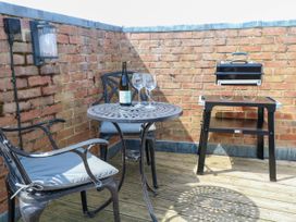 An outdoor area with a table, chairs, wine, and a grill at Skylark in Southwold