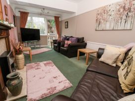 A living room with brown leather sofas wooden side tables a television on a stand pink rugs and a fireplace at The Hollies in Prestatyn