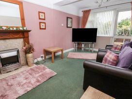A living room with fireplace television sofa and tables at The Hollies in Prestatyn