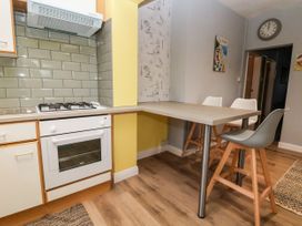 A kitchen with a gas stove oven countertop with high chairs and a wall clock at The Hollies in Prestatyn