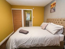 A bedroom with a bed with white sheets and pillows a folded towel on the bed two doors and a painting on the wall at The Hollies in Prestatyn