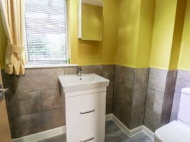 A bathroom with a sink cabinet a window with blinds and curtains and a toilet at The Hollies in Prestatyn