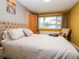 A bedroom with a bed with pillows a towel on it a chair and a window at The Hollies in Prestatyn