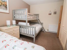A bedroom with a bunk bed a bedside table with two lamps and a wardrobe at The Hollies in Prestatyn