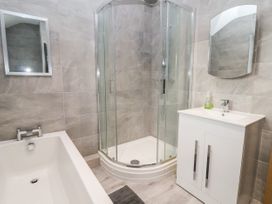 A bathroom with a bathtub shower enclosure vanity with sink and two mirrors at The Hollies in Prestatyn