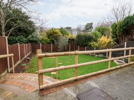 A fenced garden with green grass and stone stepping stones at The Hollies in Prestatyn