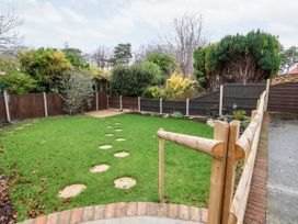 A backyard garden with a wooden fence and stepping stones on grass at The Hollies in Prestatyn