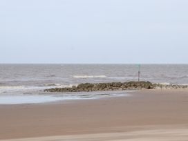 A sandy beach with a rocky breakwater and a green navigation marker in the sea at The Hollies in Prestatyn