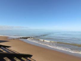 A sandy beach with steps leading down to the shore and calm sea at The Hollies in Prestatyn