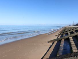 A sandy beach with waves and concrete sea defenses along the shore at The Hollies in Prestatyn