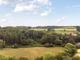 A view of trees and fields with a road at Barcud Coch - Red Kite in Garthmyl